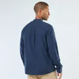 Camisa de franela azul oscuro, de manga larga, con cuello mao y cierre frontal de botones. Presenta un bolsillo de parche en el lado izquierdo del pecho.