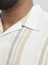 Camisa de manga corta con cuello resort y cierre frontal de botones. Presenta un diseño de rayas verticales en tonos neutros y un corte relajado.