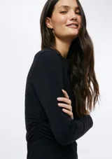 Vestido corto negro de manga larga, con escote redondo y silueta ajustada.