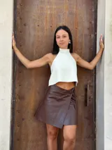 Top halter de cuero color crudo, con cuello alto y diseño corto. Se ajusta mediante tiras en la espalda.