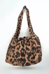 Bolso tipo saco con estampado animal print de leopardo, con asas de hombro y cierre ajustable con cordón fruncido.