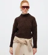 Suéter de punto texturizado con cuello alto, diseño oversized y mangas largas. Presenta una caída amplia y una superficie encorpada, ideal para un estilo moderno y acogedor.