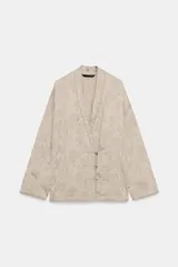 Blazer de estilo oriental confeccionado en hilatura de viscosa con tejido jacquard tono sobre tono. Presenta escote en pico, manga larga y cierre frontal cruzado con alamares a tono.