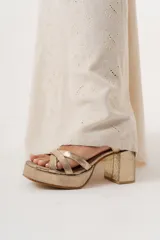 Sandalia de fiesta color champagne con triple tira delantera entrelazada y pulsera con hebilla. Plataforma delantera de 2,5 cm y taco de 8 cm.