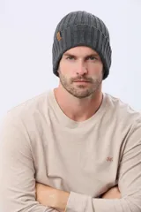 Gorro tejido de punto grueso con diseño acanalado y vuelta en el borde. Incluye una pequeña etiqueta de cuero sintético en el lateral.