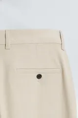 Pantalón chino de corte slim fit, confeccionado en tejido elástico. Presenta bolsillos frontales, bolsillos traseros de vivo con botón y cierre frontal con cremallera y botón.