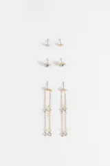 Set de tres pares de caravanas en tono dorado. Incluye un par de tachas pequeñas con forma de estrella, un par de tachas con forma de sol con piedra azul central y un par de caravanas colgantes con cadenas finas y detalles de cristales.