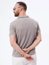 Remera polo de manga corta en tejido cloqué color gris, con cuello camisero y cierre frontal de botones.
