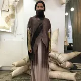 Poncho de lana merino afieltrada color marrón con cuello alto y abertura frontal.