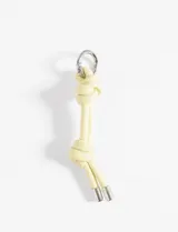 Llavero de cuero sintético color amarillo claro, con dos nudos y herrajes metálicos plateados.