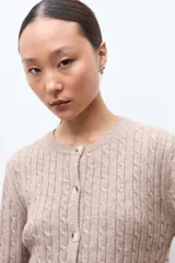 Cardigan de punto con textura de ochos, color tostado melange, con cuello redondo y cierre frontal de botones.