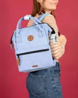 Mochila Cabaia modelo Adventurer en color celeste melange, con diseño de apertura amplia, doble asa superior, bolsillo frontal con cierre y detalles en cuero sintético marrón.