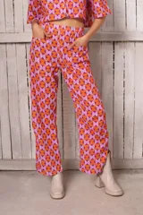 Pantalón de lino fibrana estampado con diseño geométrico en tonos naranja y lila. Tiene pretina elastizada, bolsillos delanteros y tajos laterales.