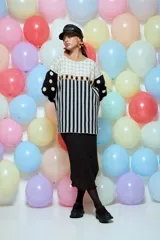 Sweater de punto con diseño geométrico y a rayas, de corte holgado y manga larga. Presenta un patrón combinado de lunares en las mangas, rombos en la parte superior y rayas verticales en el cuerpo.