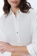 Vestido camisero blanco de lino, corte oversize, con cuello camisero, mangas largas y cierre frontal con botones.