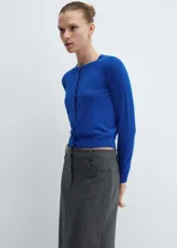 Cardigan de punto fino color azul eléctrico, con cuello redondo, manga larga y cierre frontal con botones. Presenta terminaciones en canalé y un diseño recto.