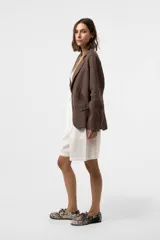 Chaqueta de lino color marrón, de calce relajado, con solapa clásica, cierre frontal de dos botones y bolsillos delanteros con solapa.