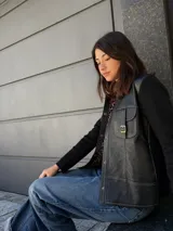 Campera negra con paneles de cuero en el frente y tejido de lana en la espalda y mangas. Presenta un bolsillo con solapa y hebilla en el pecho.