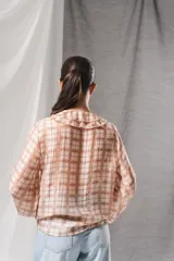 Blusa de gasa con estampado a cuadros en tonos beige y marrón, de manga larga y cuello en V con detalles de volados.