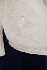 Cardigan de punto color beige, con cuello camisero, cierre frontal de botones y bolsillo aplicado en el pecho. Presenta mangas largas con puños acanalados y un corte recto y holgado.