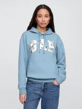 Sudadera tipo canguro de color azul claro, con capucha y bolsillo canguro frontal. Presenta el logo 'GAP' estampado en blanco con detalles florales en tonos crema y naranja.