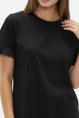 Remera blanca de algodón, de corte ajustado, con cuello redondo y mangas cortas terminadas con volados delicados.