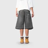 Bermuda de jean estilo baggy, color negro con efecto lavado. Presenta un corte amplio, bolsillos traseros con bordes deshilachados y detalle de bordado en uno de ellos. El ruedo también cuenta con un acabado deshilachado.