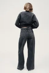 Jean de corte baggy, estilo holgado con piernas rectas, confeccionado en denim de algodón color gris oscuro con efecto lavado. Cuenta con tiro estándar, trabillas para cinto, cierre frontal con botón y cinco bolsillos clásicos.