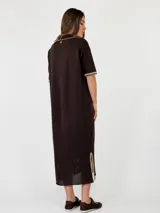 Vestido midi de punto color beige, con cuello solapa, mangas cortas y cierre frontal con botones. Presenta detalles de costuras y terminaciones en color mostaza, además de un diseño calado en el sector inferior de la falda.