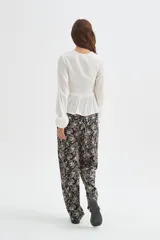 Blusa blanca de viscosa, con cuello en V, detalles de frunces en el frente, botones decorativos y mangas largas holgadas.