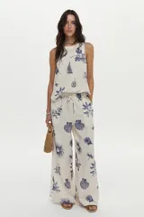 Pantalón de pierna ancha, confeccionado en lino, con cintura elástica con cordón de ajuste y estampado en tonos azules sobre base cruda.