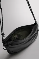 Bandolera deportiva de tejido técnico color negro, con diseño plegable y compartimento principal con cierre de cremallera. Incluye bolsillo frontal con cierre, asa de hombro ajustable con cordón técnico y detalle de logo estampado.