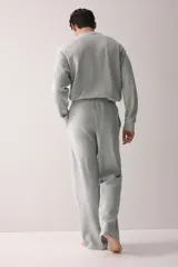 Conjunto de pijama de dos piezas en punto waffle gris claro, compuesto por una remera de manga larga con cuello redondo y un pantalón con cintura elástica y cordón de ajuste.