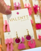 Aros colgantes con aro de acero dorado y dije circular color fucsia con borde de strass.