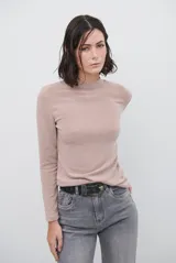 Polera de manga larga en color beige, confeccionada en tejido suave con cuello alto y corte relajado. Presenta un diseño minimalista con detalle de costura tipo collareta en la espalda.