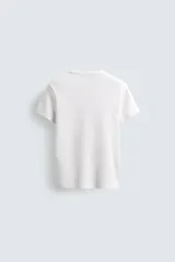 Camiseta de corte relajado, color gris claro, confeccionada en tejido con estructura waffle. Presenta cuello redondo y manga corta, con costuras decorativas en contraste color dorado que recorren los laterales y los hombros.