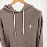 Canguro oversize color marrón con capucha, cordones blancos, bolsillo tipo canguro y logo bordado en el pecho.