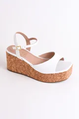 Sandalias plateadas con plataforma de corcho, tira delantera ancha y tira fina con hebilla alrededor del tobillo.