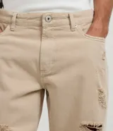 Bermuda slim de sarga color beige con diseño destroyed, rotos frontales y bolsillos.