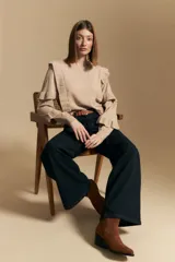 Sweater de manga larga color beige, con volados en el delantero y las mangas. De tejido suave y caída liviana, con silueta recta.