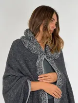 Ruana de lambswool color gris oscuro, con cuello alto y detalles bordados a mano en relieve en el cuello y a lo largo de la abertura frontal.