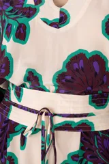 Kaftán largo con estampado floral en tonos verde, morado y blanco. Tiene escote en V, mangas largas y corte holgado.