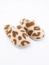 Pantuflas cerradas tipo mule, con textura de borrego o sherpa, en estampado animal print que simula manchas marrones sobre fondo beige claro.