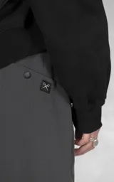Pantalón cargo oversize de color gris, confeccionado en tejido técnico ripstop. Cuenta con cintura elástica con presillas, cierre frontal con broche técnico, múltiples bolsillos amplios y sistema de ajuste con broches snap en los tobillos.