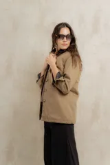 Campera color beige con cuello de corderito negro, cierre frontal con botones y forro interior. Presenta un diseño de corte recto y mangas largas con puños vueltos.