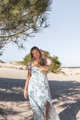 Vestido midi blanco con estampado floral en tonos verdes, escote en V, mangas cortas abullonadas y corte evasé con abertura lateral.