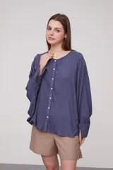 Camisa de corte holgado y diseño amplio, con cuello redondo y cierre frontal de botones. Presenta mangas largas con caída fluida y puños sencillos.