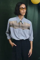 Camisa negra de manga larga con canesú frontal estampado con motivos artísticos de bodegón. Incluye una corbata fina integrada del mismo tono.