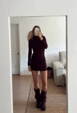 Vestido corto de manga larga en color bordó, con cuello alto y diseño ajustado con frunces laterales que recorren toda la prenda.