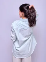 Camisa de manga larga a rayas verticales celestes y blancas, de corte suelto, confeccionada en algodón.